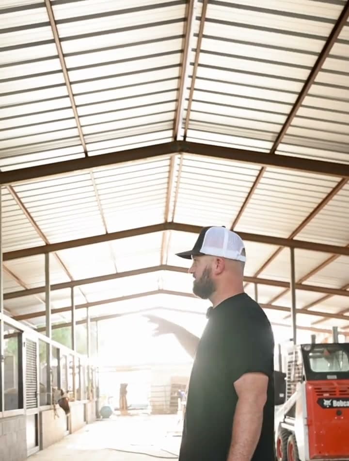 Inside the Zona Ranches barn — steel frame, block stall walls and a concrete aisle